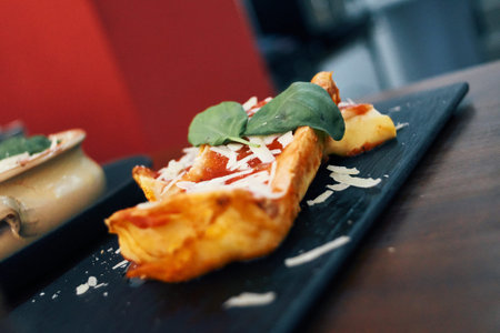 A plate of food with a piece of cheese and a piece of spinach on top. The plate is on a table