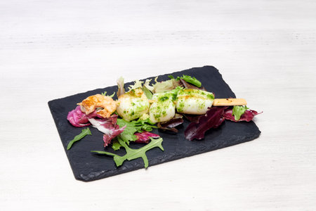 A plate of food with a piece of broccoli on it. The plate is placed on a white table. The broccoli is cut into small pieces and is surrounded by other vegetables such as lettuce and carrotsの写真素材