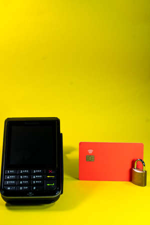 A card terminal in a yellow background with a padlock and a cardの写真素材