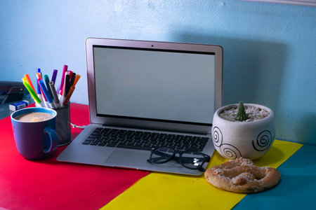 desk office with laptop, blank notepad, coffee cup suggar pretzel and pen on wood table.の写真素材