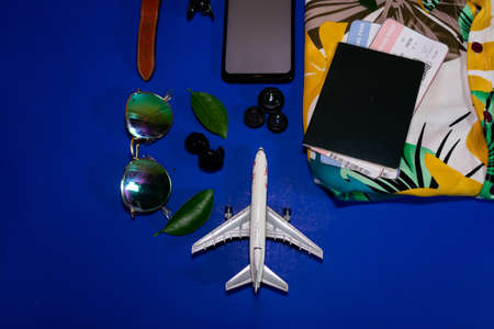 Preparation for Traveling concept, watch, airplane, passport, earphone, eyeglass on blue background with copy space.の写真素材