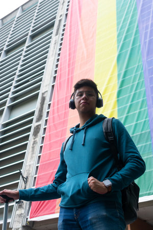 young man looking at the camera proud in a lgbt flag at the backgroundの写真素材