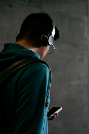 Young man listening to music with headphones and smartphone on the dark backgroundの写真素材