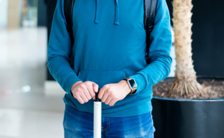 An unrecognizable traveler poses with a suitcase and a smartwatchの写真素材