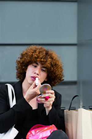 A non-binary person applies makeup sitting on a benchの写真素材