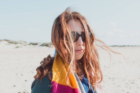 young woman with scarf and casual hair by the windの写真素材