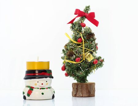 Snowman candle by a small christmas treeの写真素材