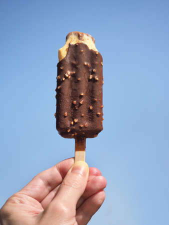 Hand with refreshing ice cream against blue skyの写真素材