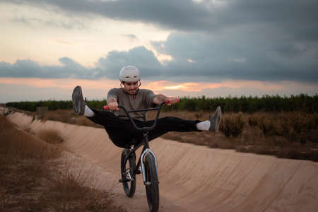 Young bmx rider wearing a white helmet juggling with the bike outdoors. No-footer trickの写真素材