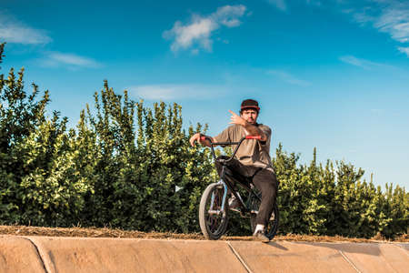 Young male bmx rider sitting on the bike making the horn hand "corna" signの写真素材