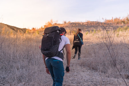 Young backpacker man with a   mask holding in the hand and blonde ponytail woman hiking in the...