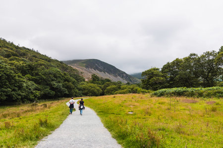 two people on their backs walking along a path in the direction of a mountain in a natural green...