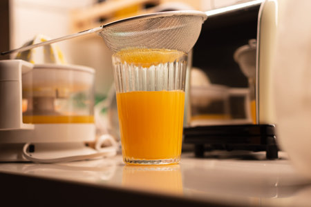 straining the orange juice into a glassの写真素材