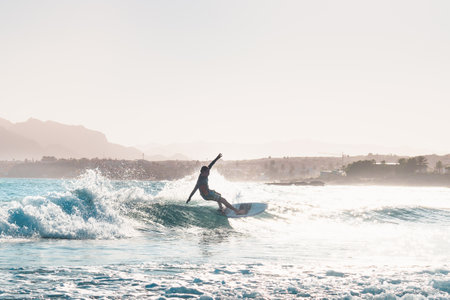 young male surfer riding a wave in the afternoonの写真素材