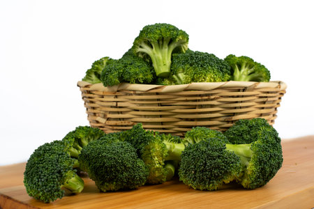 broccoli in a basket on a wooden board on a white backgroundの写真素材