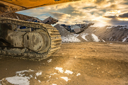 Stone crusher and excavator in an open pit mine. Granite mine to make gravel