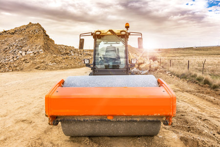 Compactor doing earth compaction work for later asphalting in a road construction