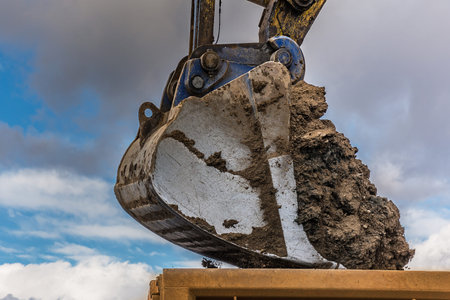 Detail of a shovel of an excavator loaded with dirt to build a road