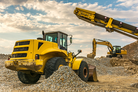 Excavators and heavy machinery in the works of stone movement in a quarry stone extraction for its transformation into gravelの写真素材