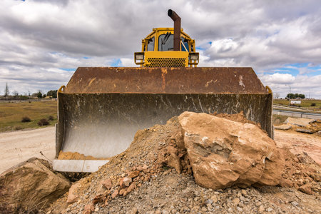 Large amount of stone and earth moved by a yellow excavator