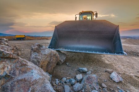 Excavator moving stone and rock in a quarry or at a construction siteの写真素材