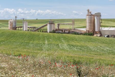 Cement factory on a green meadow in springの写真素材