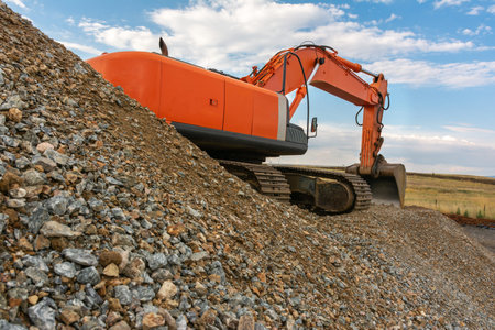 An excavator moving gravel for the construction of a road