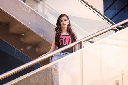 Portrait of young brunette girl in fashionable pose on the streetの写真素材