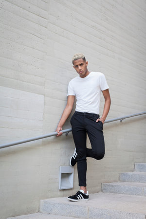 From below of African American male in elegant white shirt looking at camera while standing against...