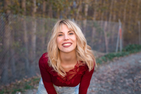 Graceful young calm female model with long blond hair in blouse with dry spiky plant in hand looking...
