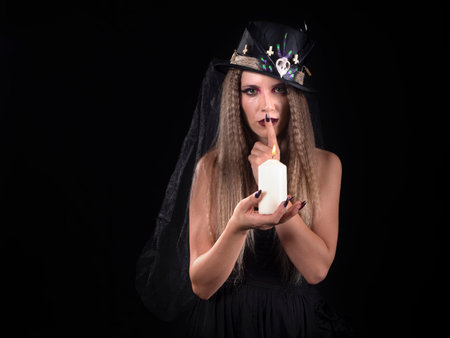 Portrait of a woman looking at camera on halloween doing voodoo to a dollの写真素材