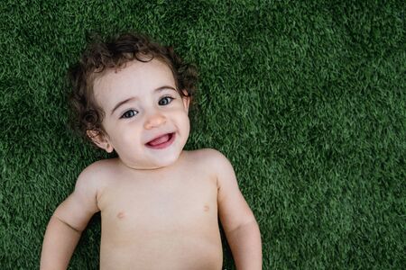 Two years old girl smiling lying on the grassの写真素材