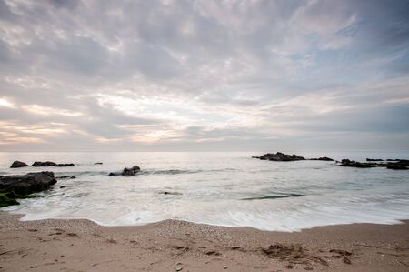Long exposure beach with fine sand and cloudy skyの写真素材