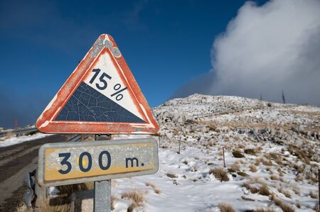 triangular sign indicating the unevenness of a high mountain road. Background with snow in the backgroundの写真素材