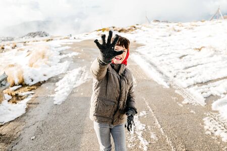 eight year old boy laughing and playing throw snow at the camera in the midle of a secondary roadの写真素材
