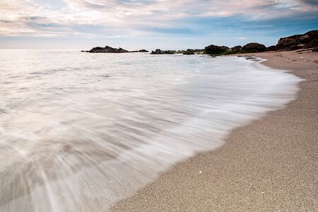 Long exposure beach with fine sand and cloudy skyの写真素材
