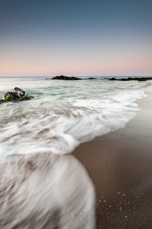 Long exposure beach with fine sand and cloudy skyの写真素材