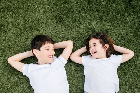 brothers lying face up on the grass at home smiling and playing with each otherの写真素材