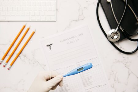 view of a doctors hands explaining the diagnosis of coronavirus with his tablet on his desk surrounded by medical materialの写真素材