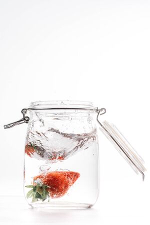 clear water can piece of fresh strawberry falling at high speedの写真素材