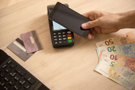 Hand of man paying with contactless credit card with NFC technology, credit card reader, payment terminal, finance and banking conceptの写真素材