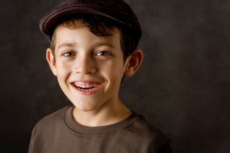 smiling kid looking at camera with a brown vintage capの写真素材