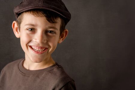 smiling kid looking at camera with a brown vintage capの写真素材