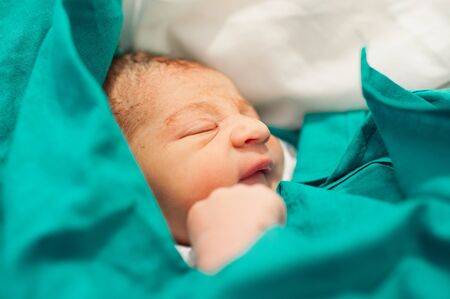 Close up newborn baby. First minutes of life. Newborn baby wrapped in the bedsheet of the hospitalの写真素材
