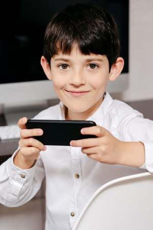 A young boy holding a phone looking at camera in his work zoneの写真素材