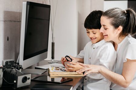 boy studying with his mature mother and looking through a magnifying glassの写真素材