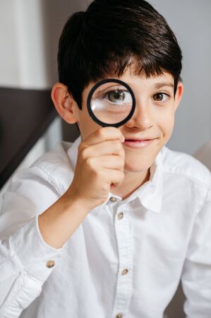 Boy holding and looking through magnifying glassの写真素材