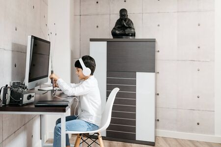 A little boy wearing a white shirt holding for a photo with white headphonesの写真素材