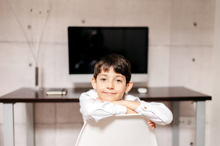 bored boy lying on a chair with his workspace in the background out of focus