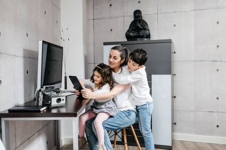 Middle-age mother with her children using digital tablet in workspaceの写真素材